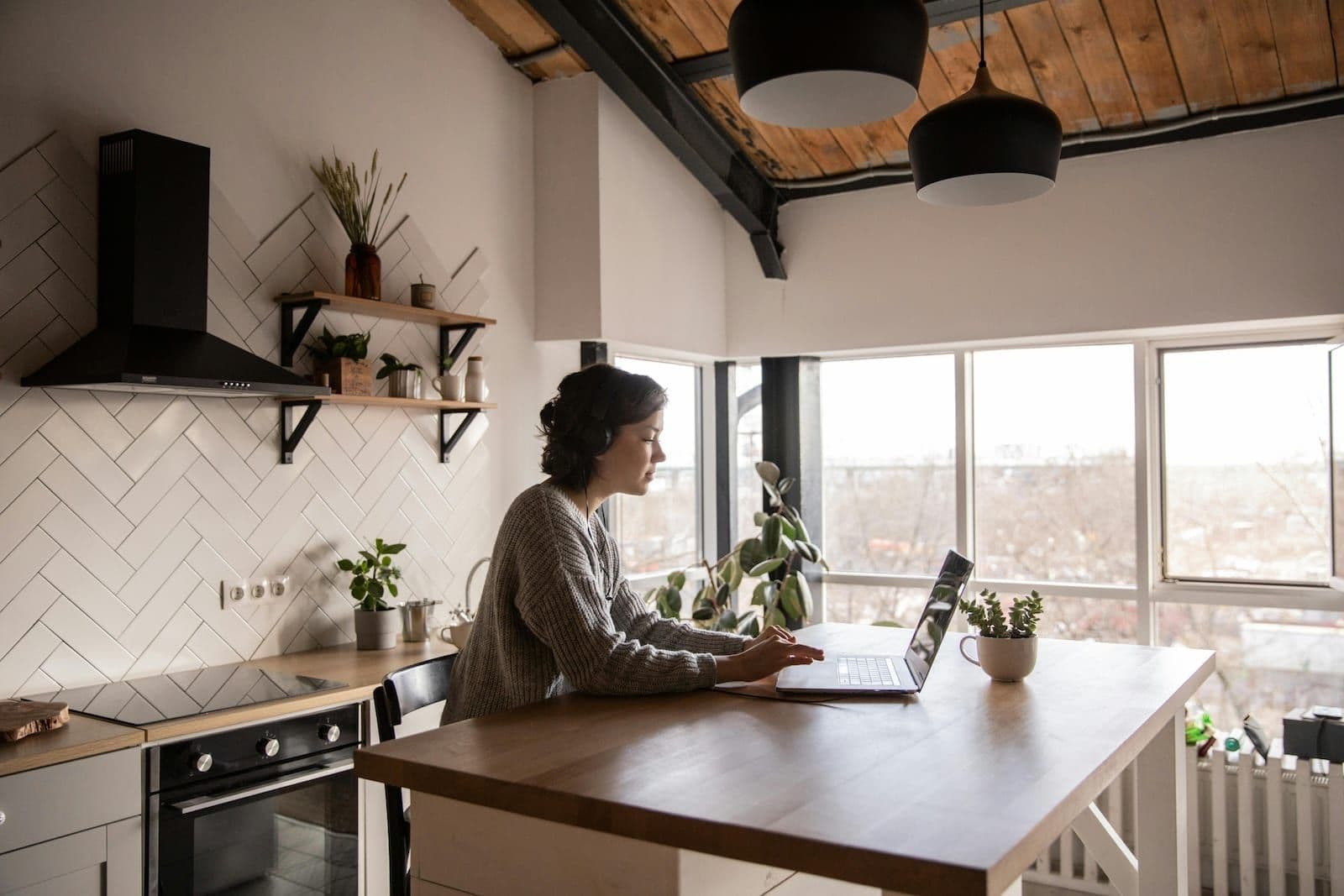 Opositora estudiando con el portátil y auriculares en la mesa de su casa