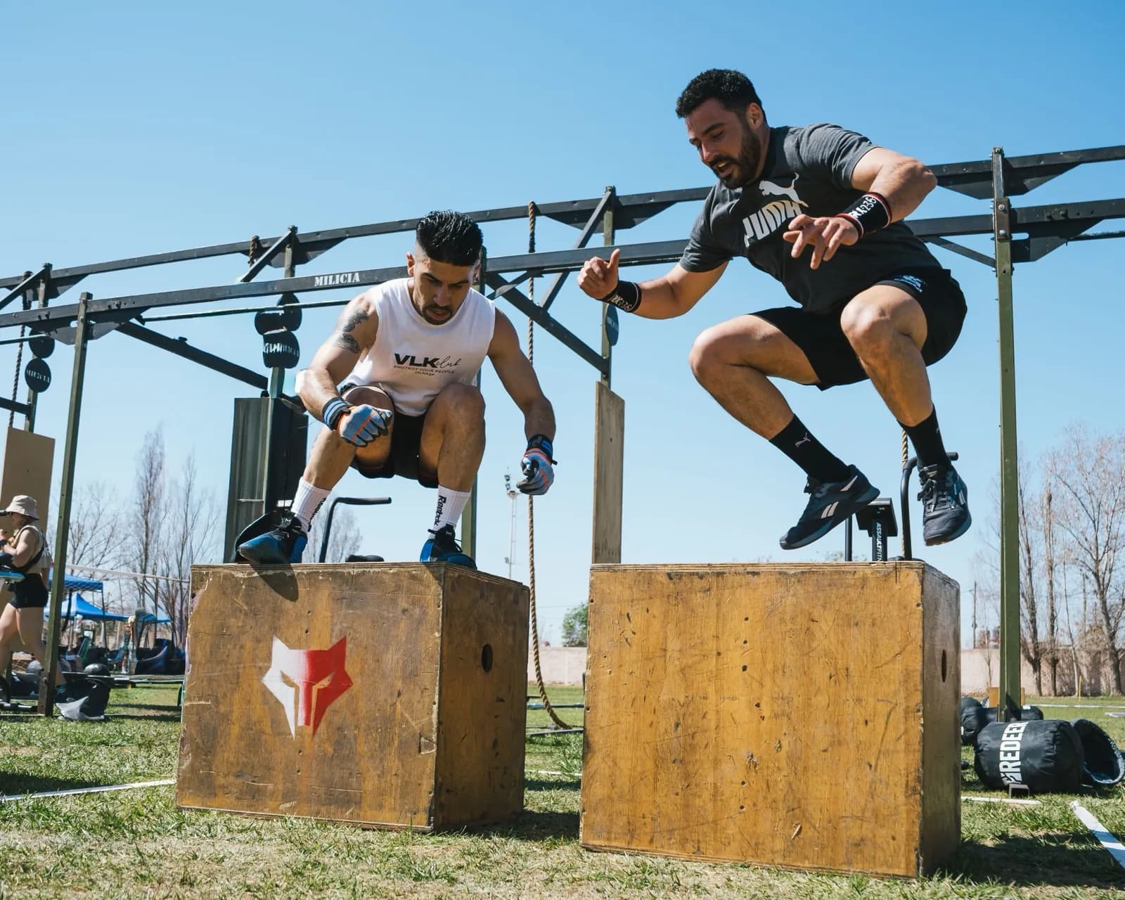 Dos deportistas saltando sobre cajones en un entrenamiento al aire libre